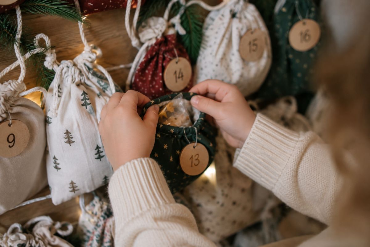 Kind öffnet eines der 24 Adventskalender-Säckchen mit einer kleinen Überraschung in der Hand.