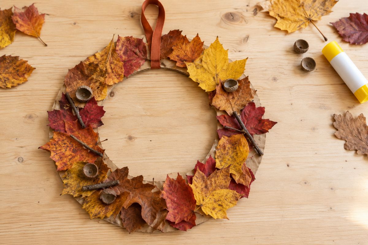 Herbst basteln mit Kindern: Kranz aus bunten Blättern, Zweigen und Eichelhütchen