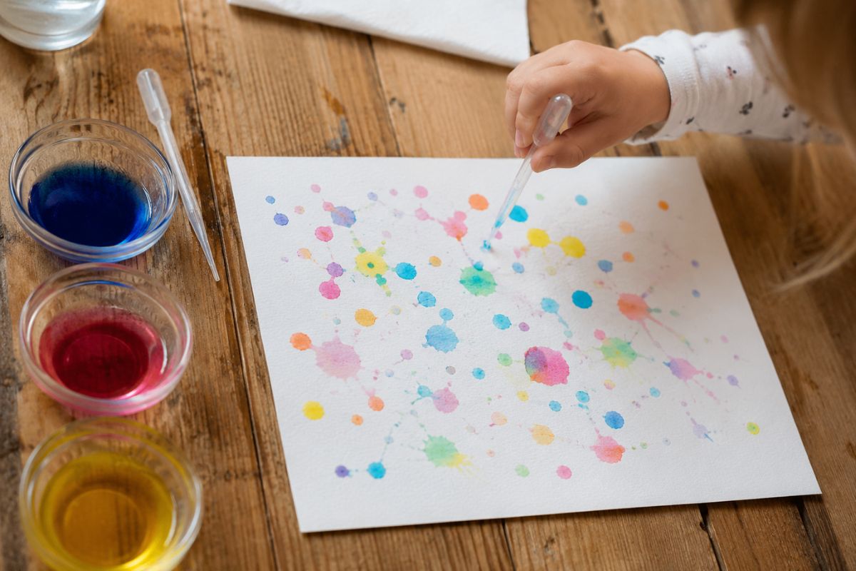 Kind gestaltet bunte Regentropfenbilder mit einer Pipette und eingefärbtem Wasser auf Papier