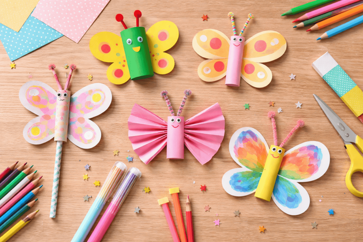 Bunte Schmetterlinge aus Papier, von Kindern gebastelt und bemalt, mit einfachen Formen und unperfekten Mustern