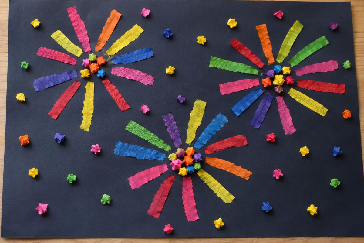 Feuerwerk basteln mit Krepppapier: Von einem Kind gestaltetes Feuerwerk auf schwarzem Papier mit bunten Krepppapierstreifen und locker geknüllten Krepppapierkügelchen als Lichtpunkte